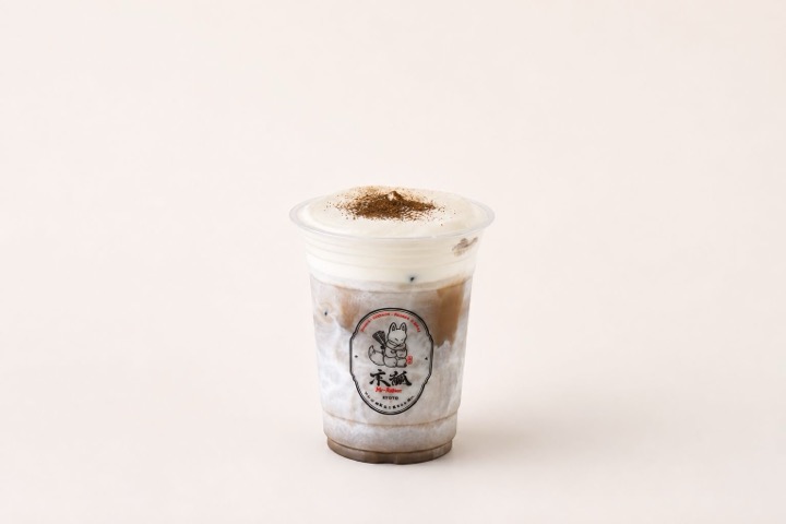 Iced hojicha latte crowned with cream foam and dusted with roasted tea powder
