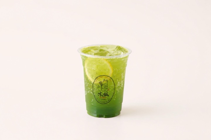Bright green matcha lemon soda over ice with fresh lemon slices